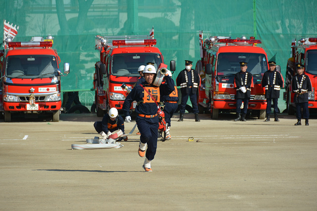 甲斐市消防団出初式にて消防団員がポンプ車を操法している写真